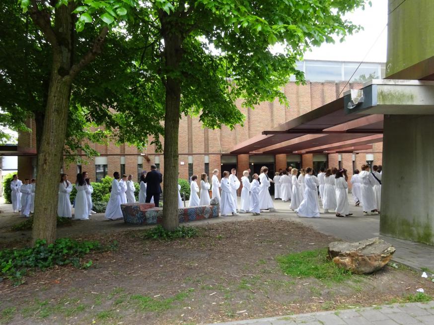 In hun uniforme witte alben stappen de vormelingen van de parochies Pius X en O.L.V.-Middelares de kerk binnen. © Marjo Perry