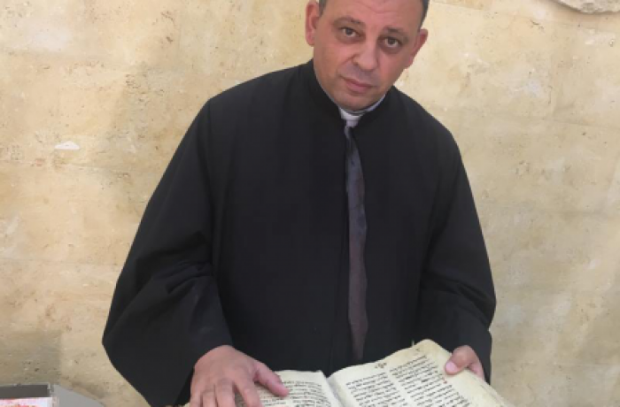 De pastoor van Erbil neemt ontroerd de oude kerkboeken in ontvangst van het islamitische gezin dat ze onder IS bewaarde.  © Asianews