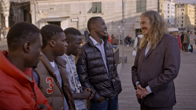 Ilja Leonard Pfeijffer spreekt met enkele vluchtelingen in de straten van Genua. © NPO2
