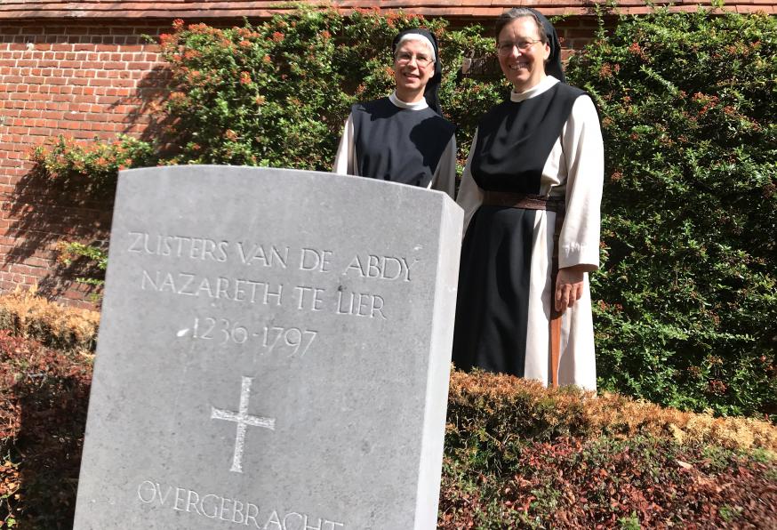 Zuster Anna (links) en zuster Katharina bij de grafsteen waar de resten begraven liggen van zusters van de abdij in Lier. © Lieve Wouters