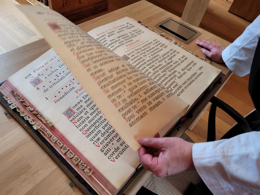 Broeder Benedikt bladert in een oud koorboek, in koper gedrukt in de abdij van Westmalle. Vroeger bezat ze een eigen drukkerij voor Latijnse teksten. © Ilse Van Halst