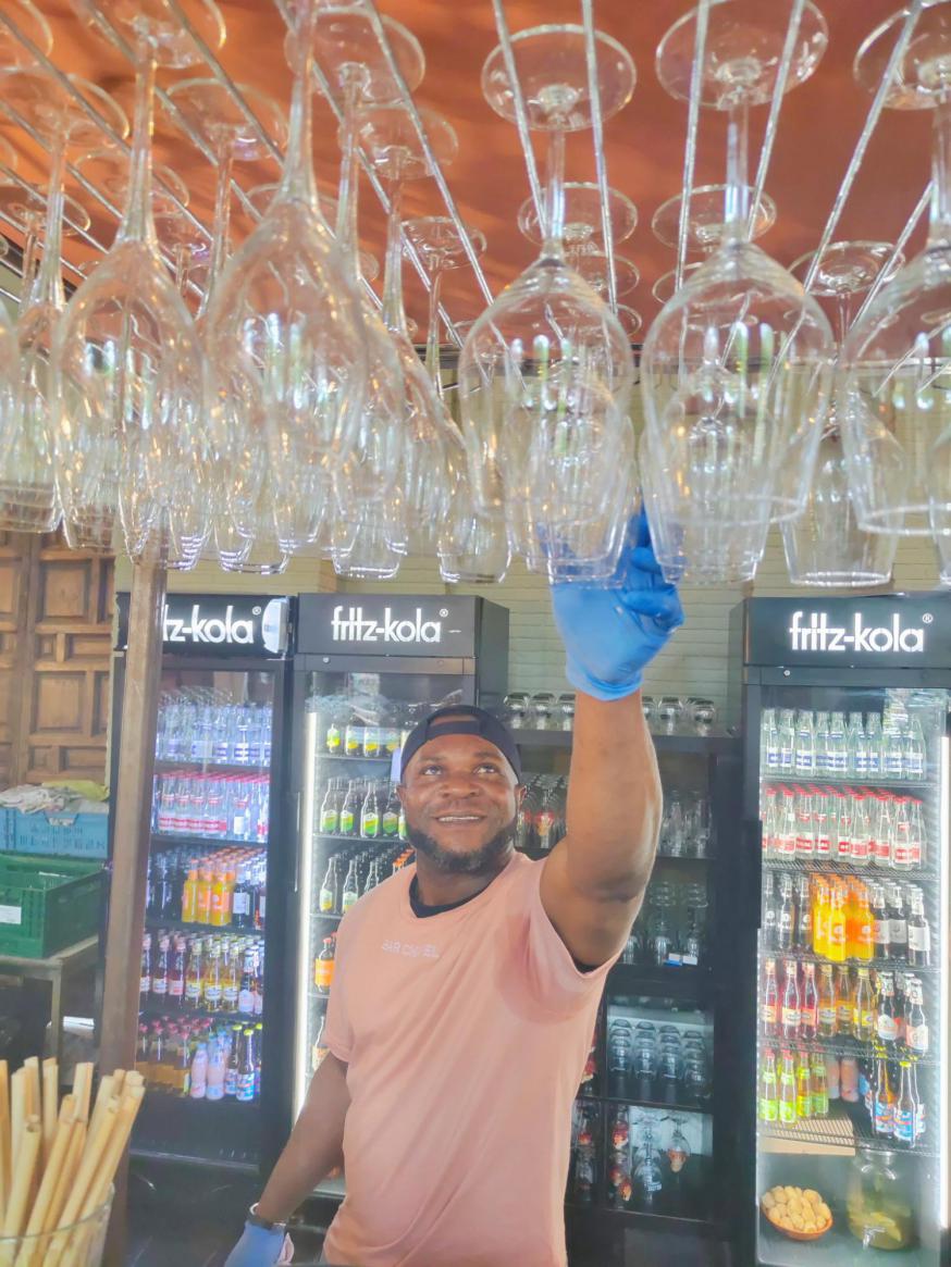 Daniël uit Nigeria, hier aan toog in Bar Chapel, wil niets liever dan legaal werken in België. © Pax Christi