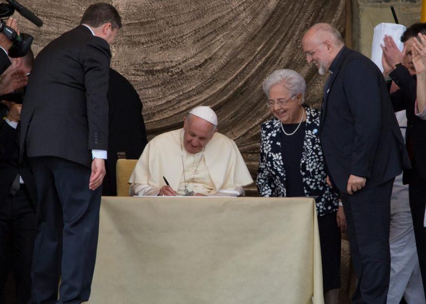 Paus Franciscus ontvangt als geschenk een manifest ondertekend door alle inwoners van het Focolarestadje. Daarin beloven ze verder te werken aan broederlijkheid en dialoog. Paus Franciscus ondertekent mee. © Focolare