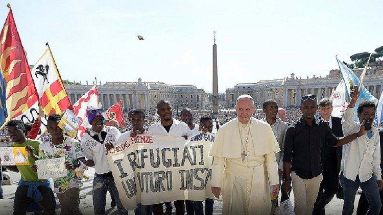 Paus Franciscus omringd door enkele vluchtelingen © Caritas